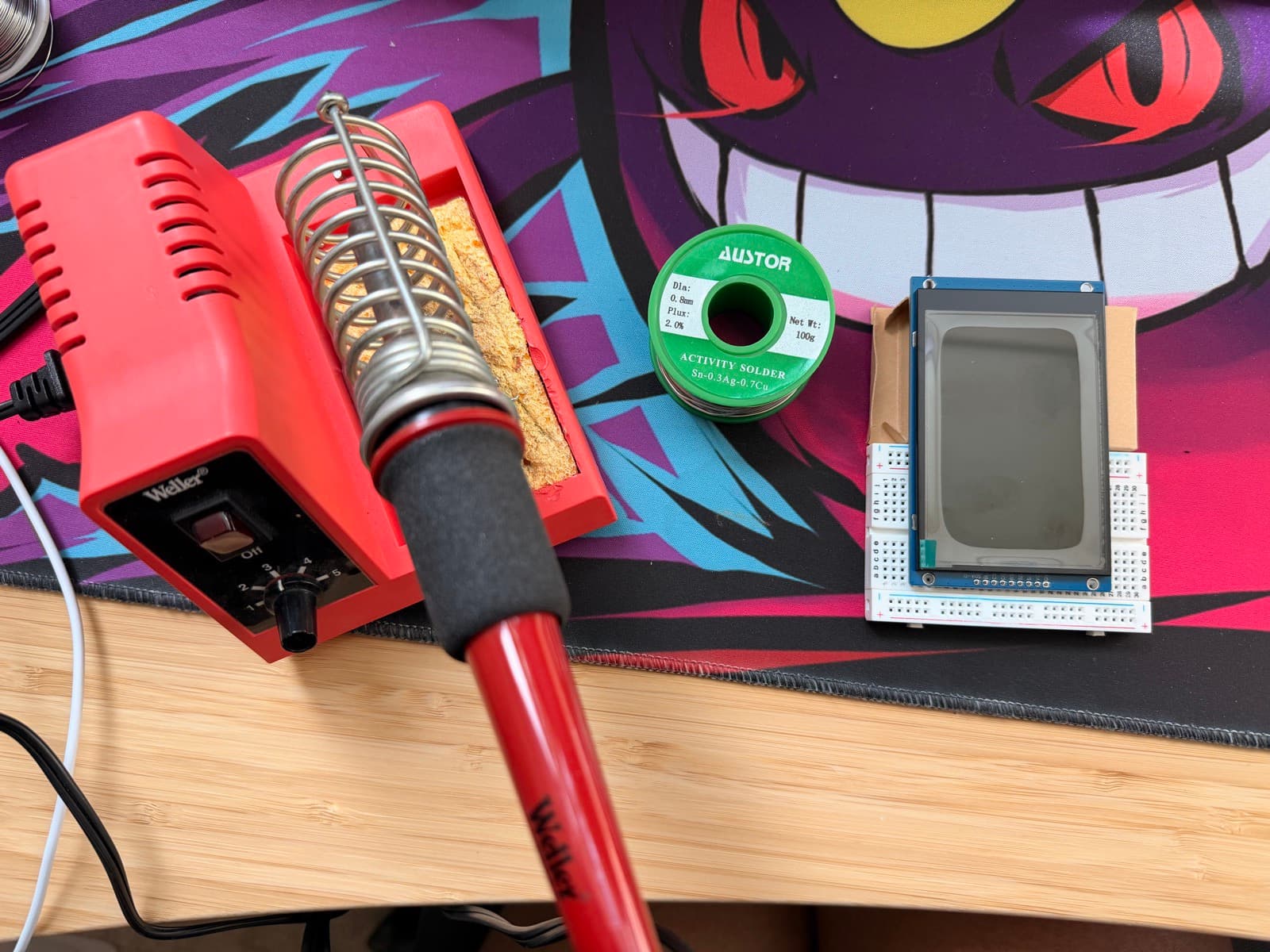 Soldering station setup: a Weller iron in its stand, a spool of lead-free solder, and the display resting on the breadboard jig